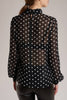 A black silk blouse with white polka-dots has button fastenings at neck and cuffs.
