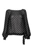 The blouse is cut in a loose fit from black silk with white polka-dots. It has blouson sleeves and a decorative bow.