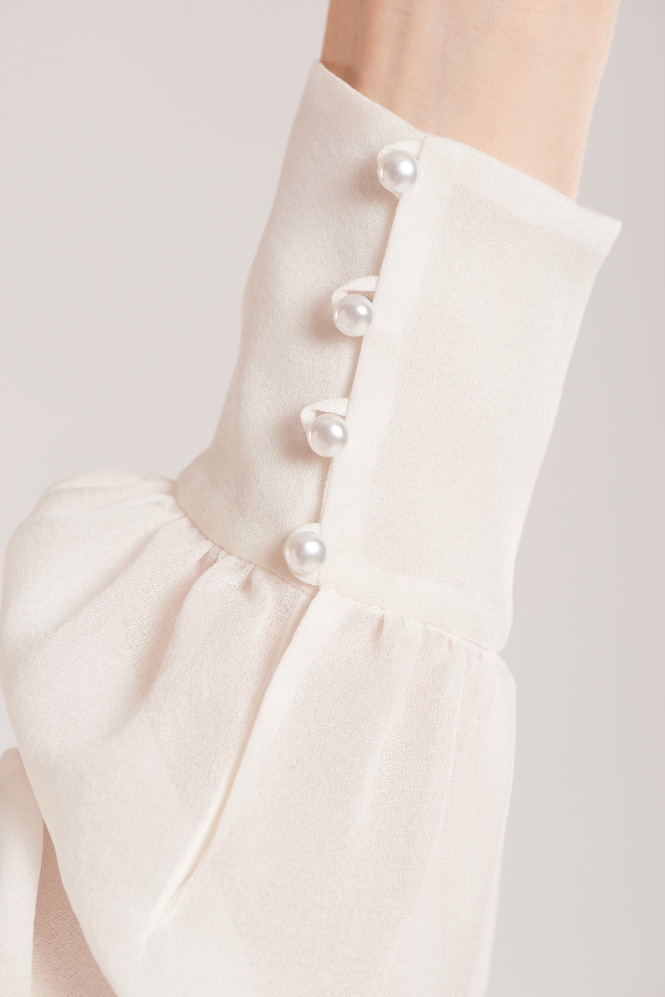 This versatile ivory silk blouse has a pearl button fastening at neck and cuffs.